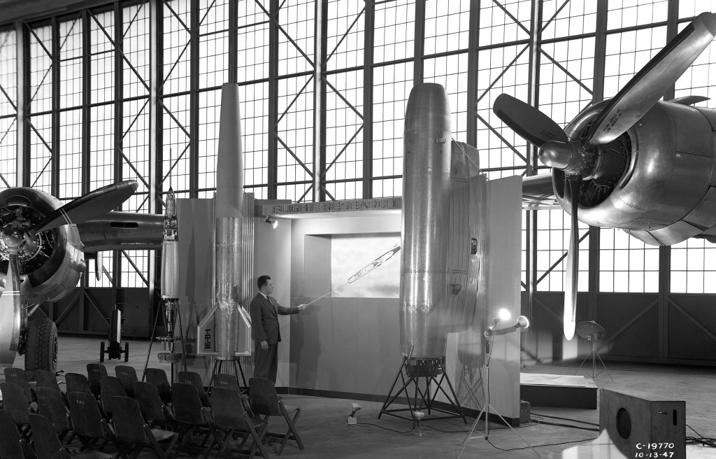 Man with exhibit in hangar.