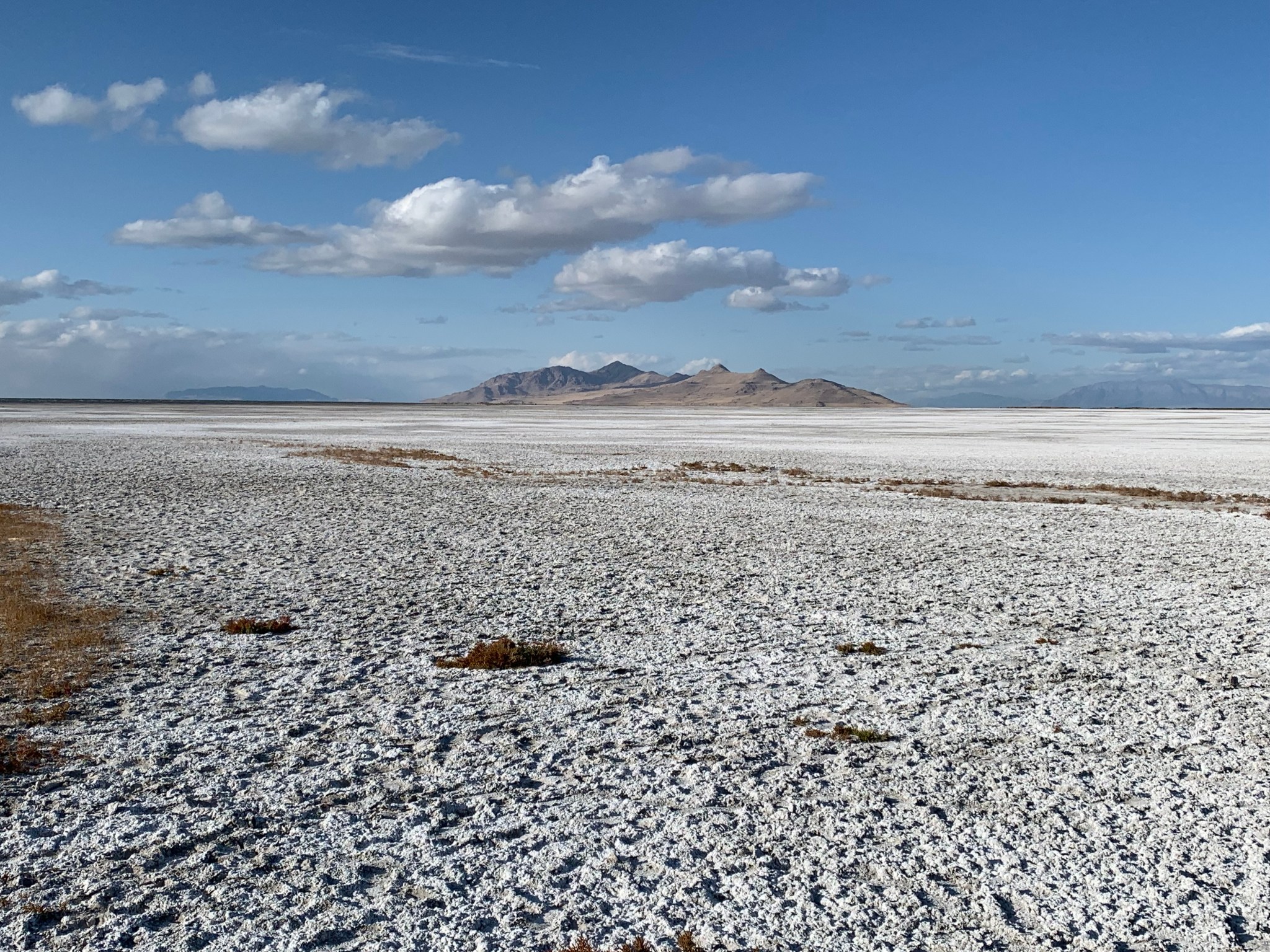 This is a photgraph of the dry lakebed of the Great Salt Lake extending into the distance where the is a large, far off mountain range.
