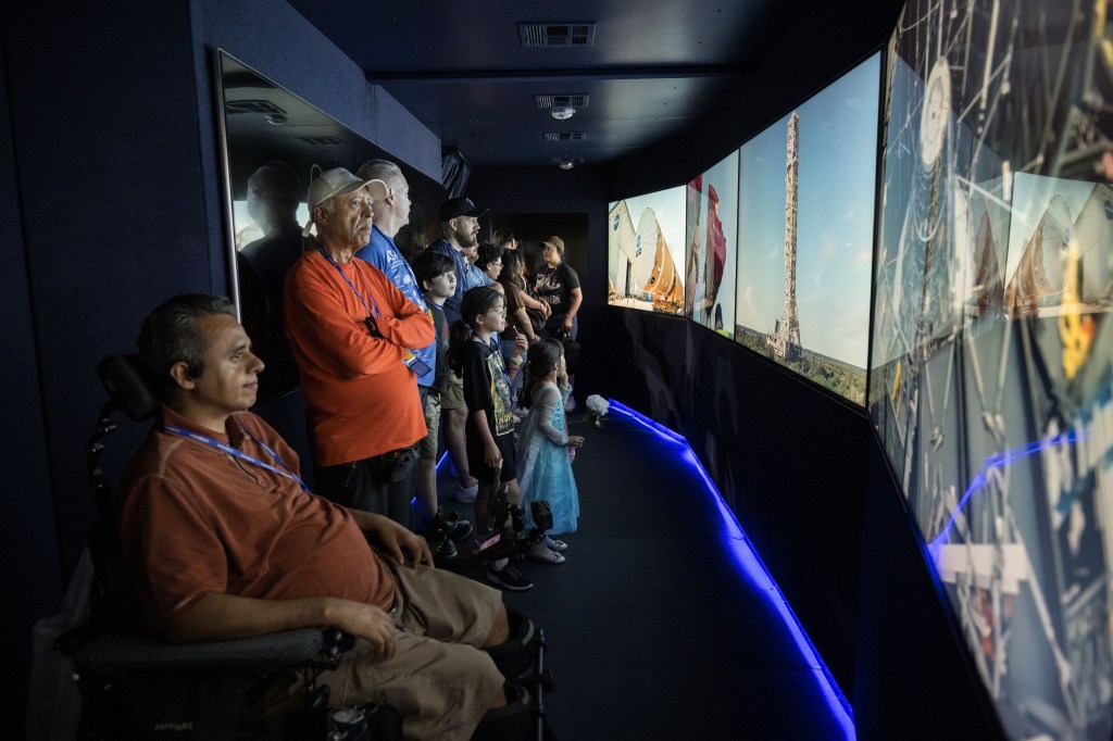 A group of people watch a presentation inside a NASA trailer.