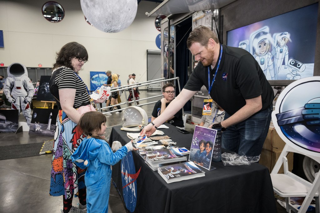 A mother and child visit a NASA table at Comicpalooza.