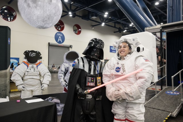 A person in a Darth Vader costume stands next to a person in a spacesuit.