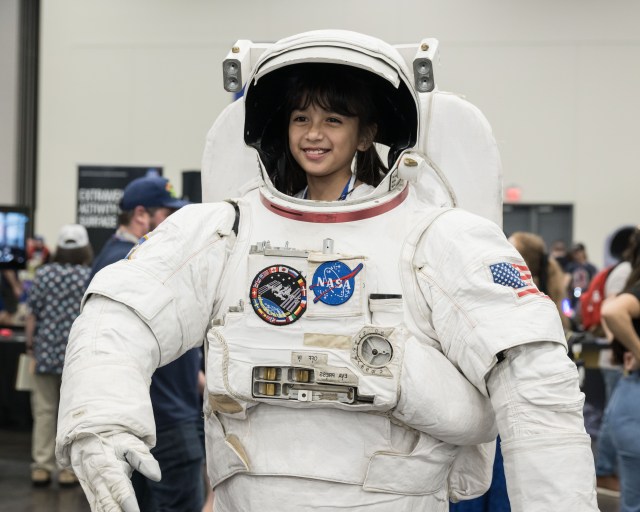 A diverse group of children and adults enjoy a NASA exhibit booth at Comicpalooza.