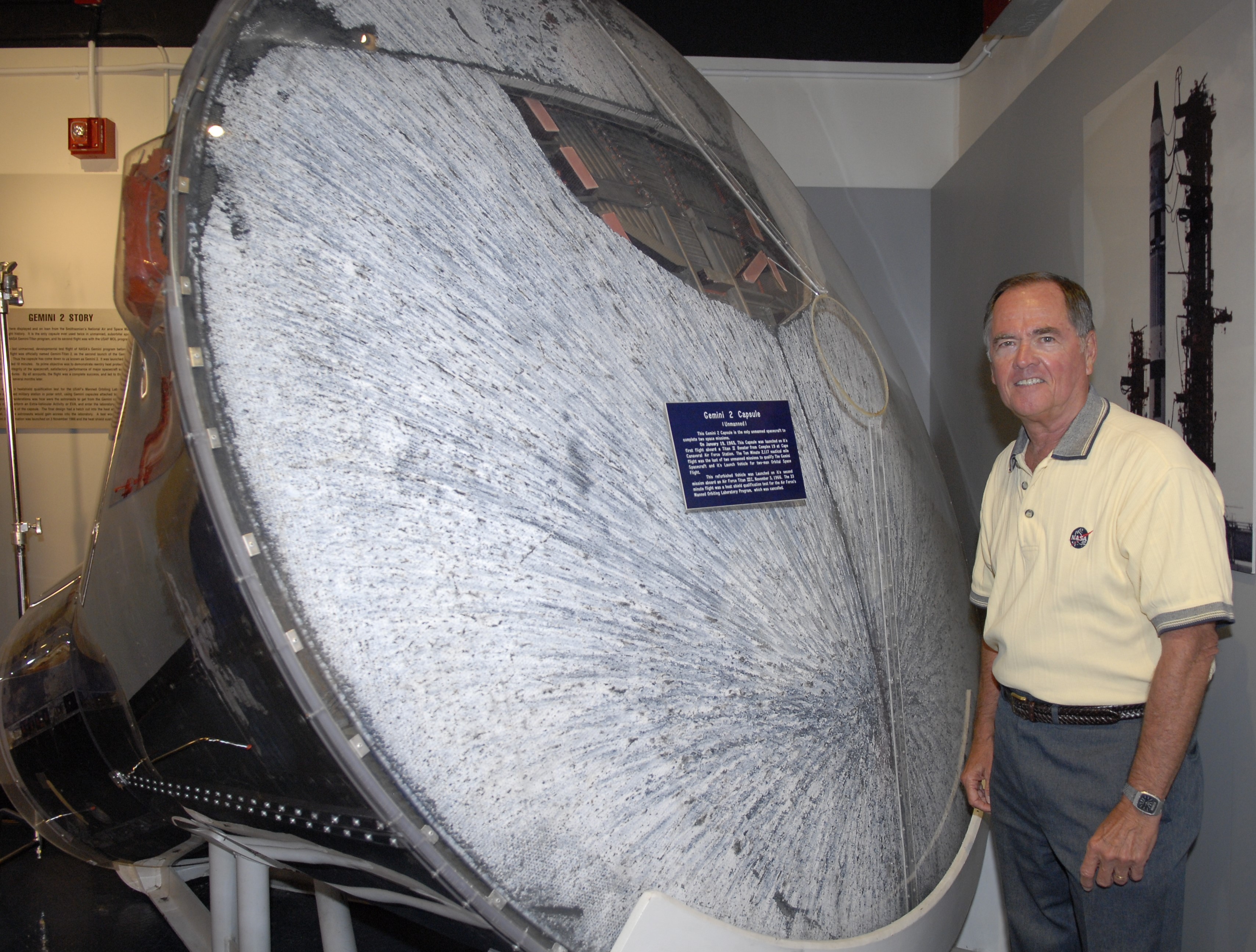 Former MOL and NASA astronaut Robert L. Crippen stands beside the only flown Gemini-B capsule – note the hatch in the heat shield at top