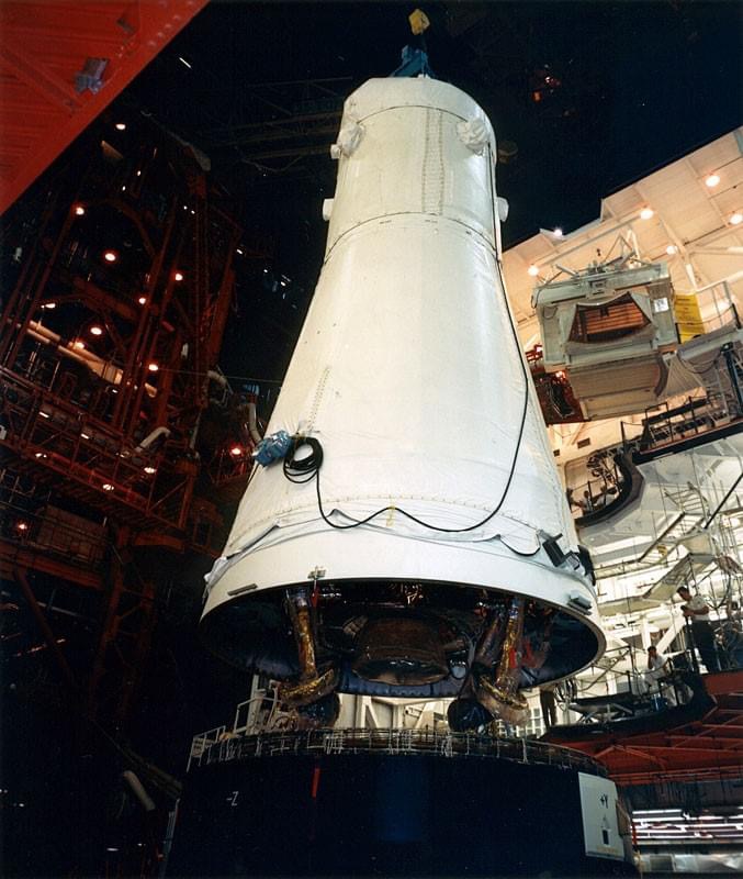 In the VAB. workers lower the Apollo 12 spacecraft onto its Saturn V rocket