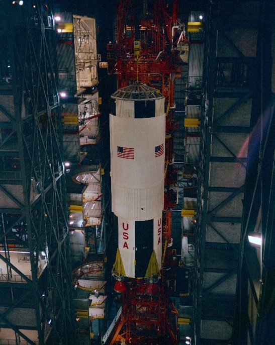 In the Vehicle Assembly Building at NASA’s Kennedy Space Center (KSC) in Florida, workers place the first stage of the Apollo 13 Saturn V rocket onto the Mobile Launcher to begin the stacking process