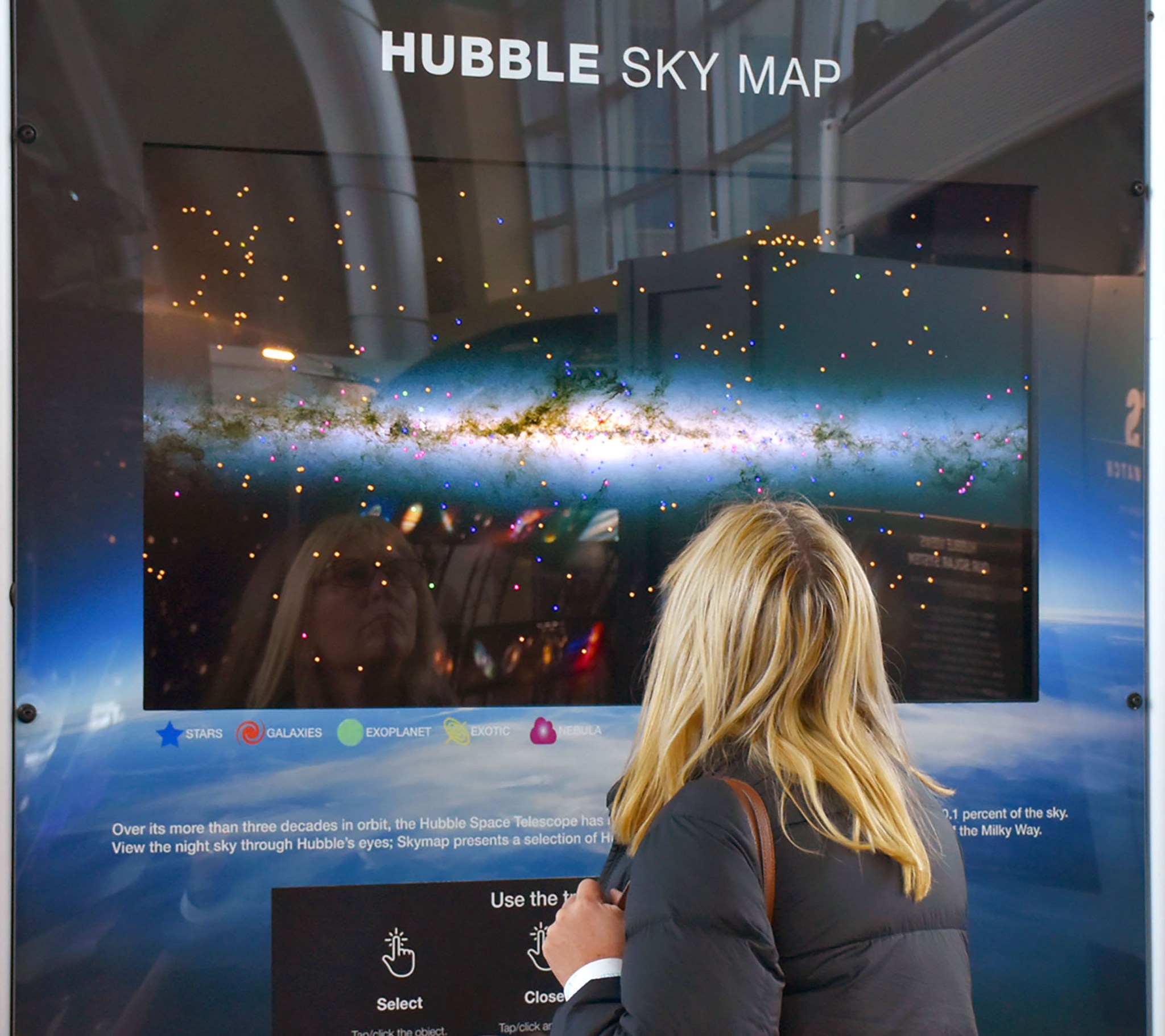 A women looking at a digital display of the Hubble Sky Map.