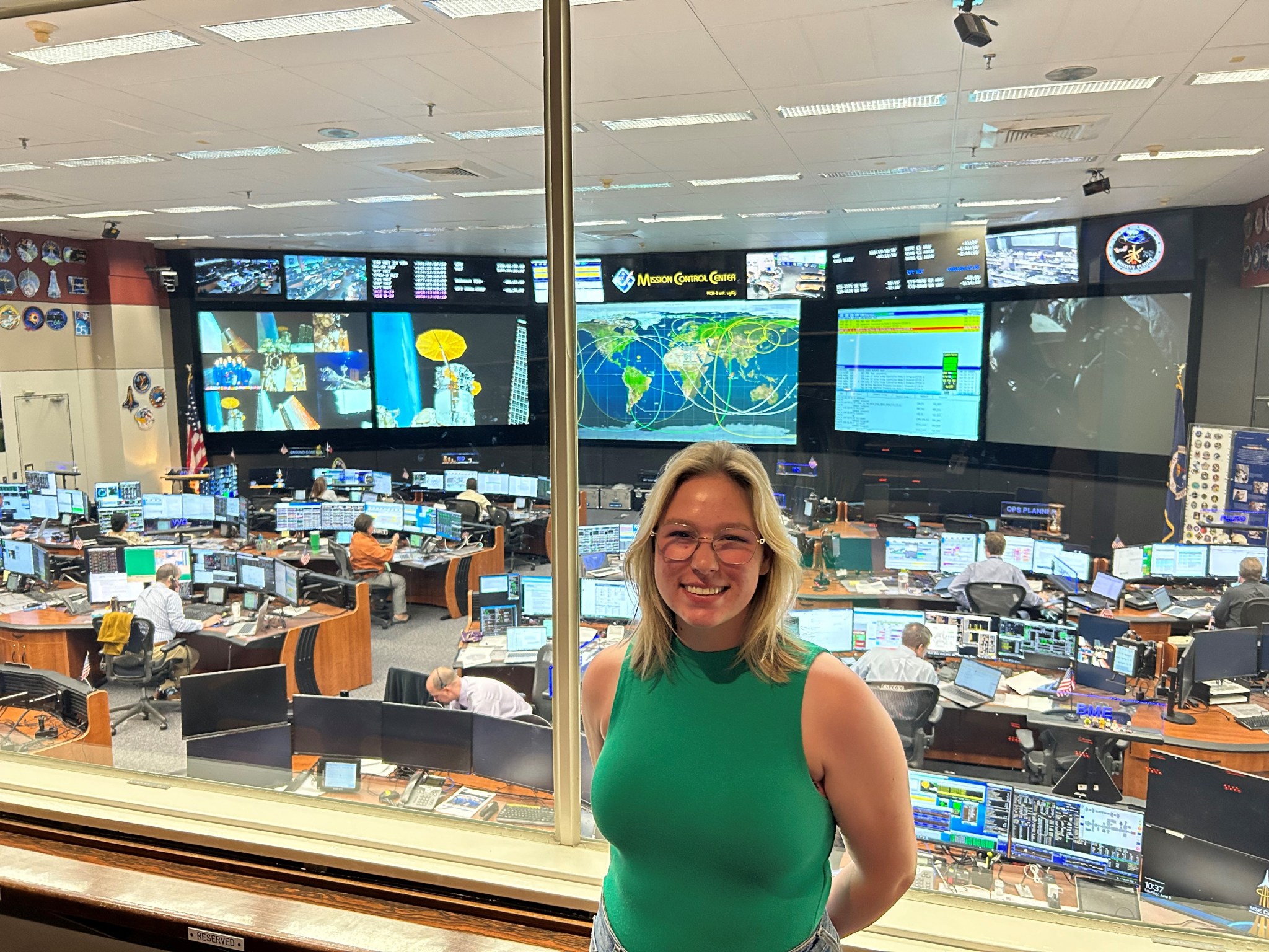 A young woman poses for a photo in the viewing room at the Mission Control Center at Johnson Space Center.