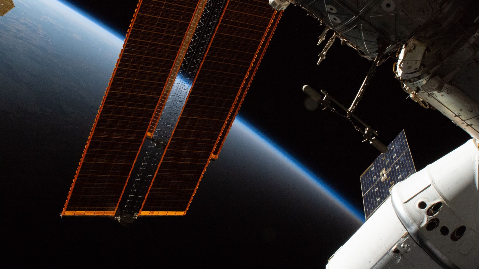 The SpaceX Dragon resupply ship (at right) and a pair of the International Space Station's main solar arrays foreshadow a trek into an orbital sunset.