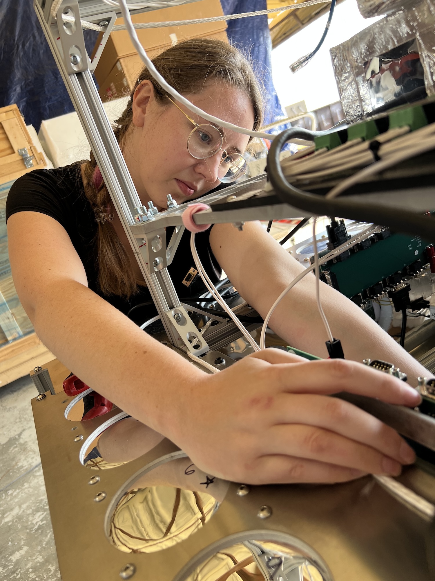 Closeup of student researcher with braided hair and glasses adjusting experiment.