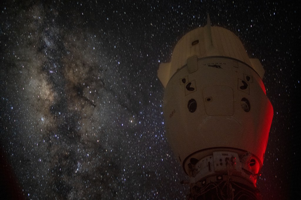 The Milky Way appears in the vastness of space behind the dimly lit SpaceX Dragon Endeavour spacecraft docked to the Harmony module's space-facing port on the International Space Station.