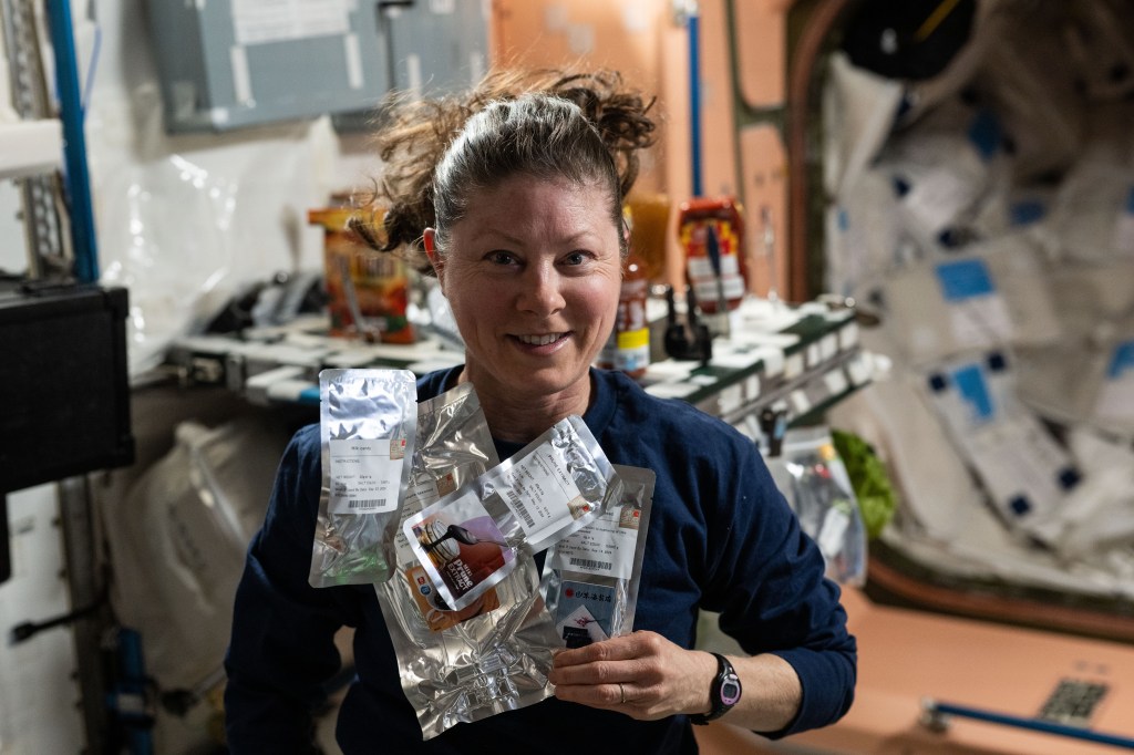 NASA astronaut and Expedition 71 Flight Engineer Tracy C. Dyson is pictured in the galley aboard the International Space Station's Unity module showing off food packets from JAXA (Japan Aerospace Exploration Agency).
