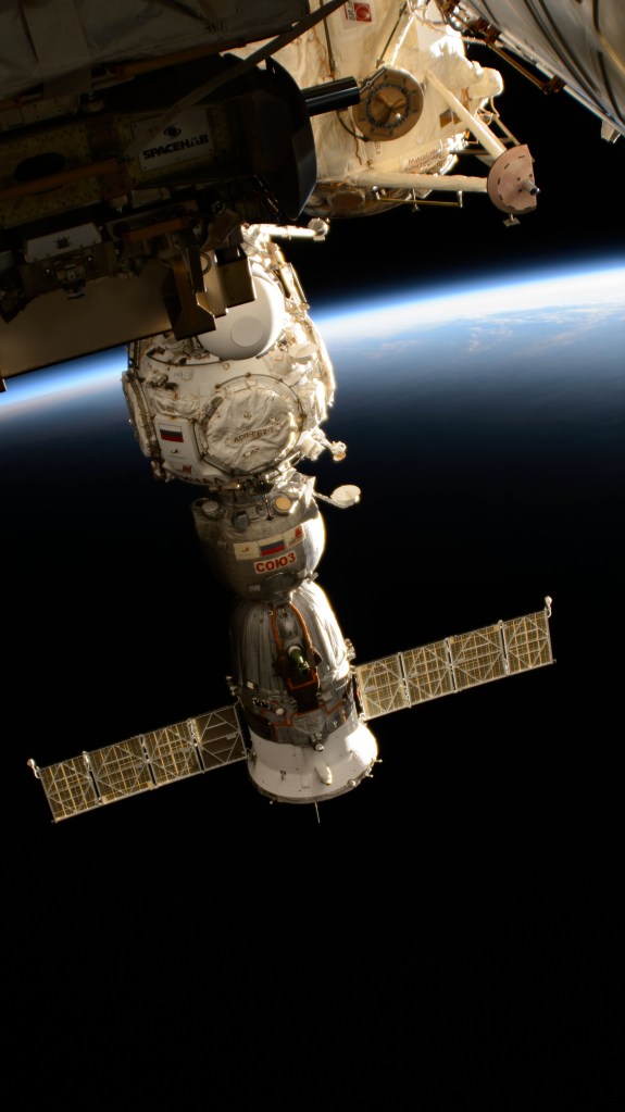 The Soyuz MS-25 crew ship is pictured docked to the Prichal docking module on the Roscosmos segment of the International Space Station while orbiting into a sunset 259 miles above Alaska's Aleutian Islands.