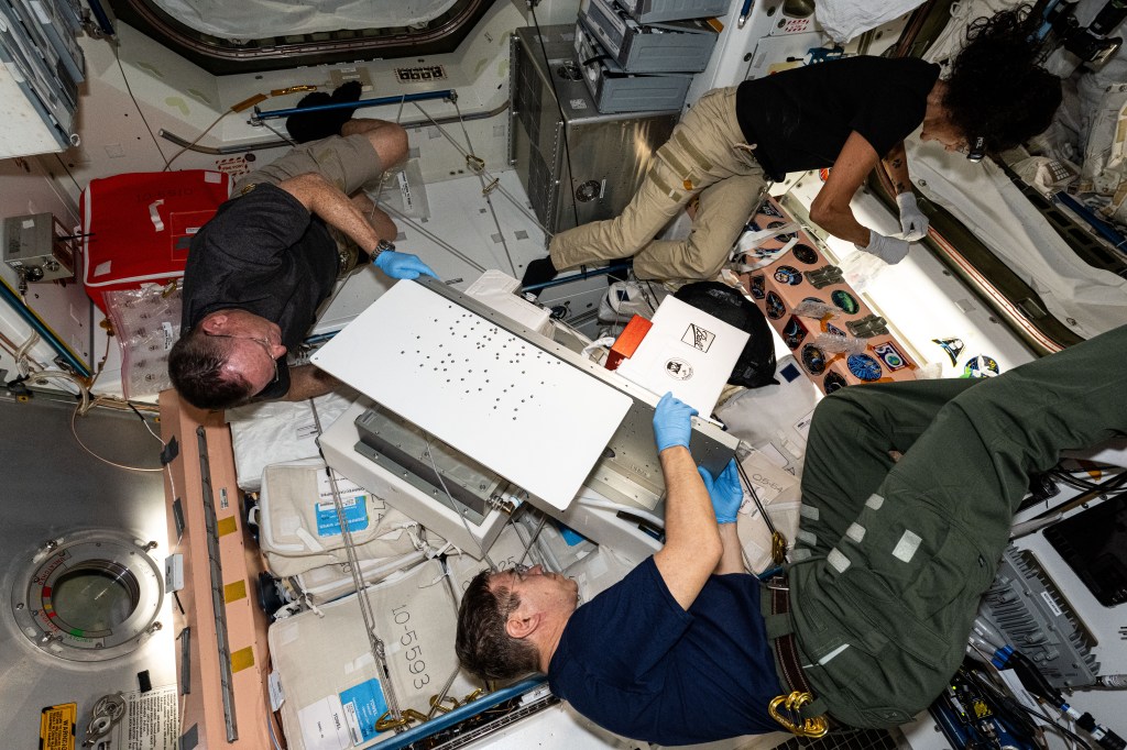 Clockwise from bottom, NASA astronauts Mike Barratt, Butch Wilmore, and Suni Williams are at work inside the International Space Station's Unity module. The trio was configuring the ArgUS Mission 1 technology demonstration hardware to test the external operations of communications, computer processing, and high-definition video gear in the vacuum of space.