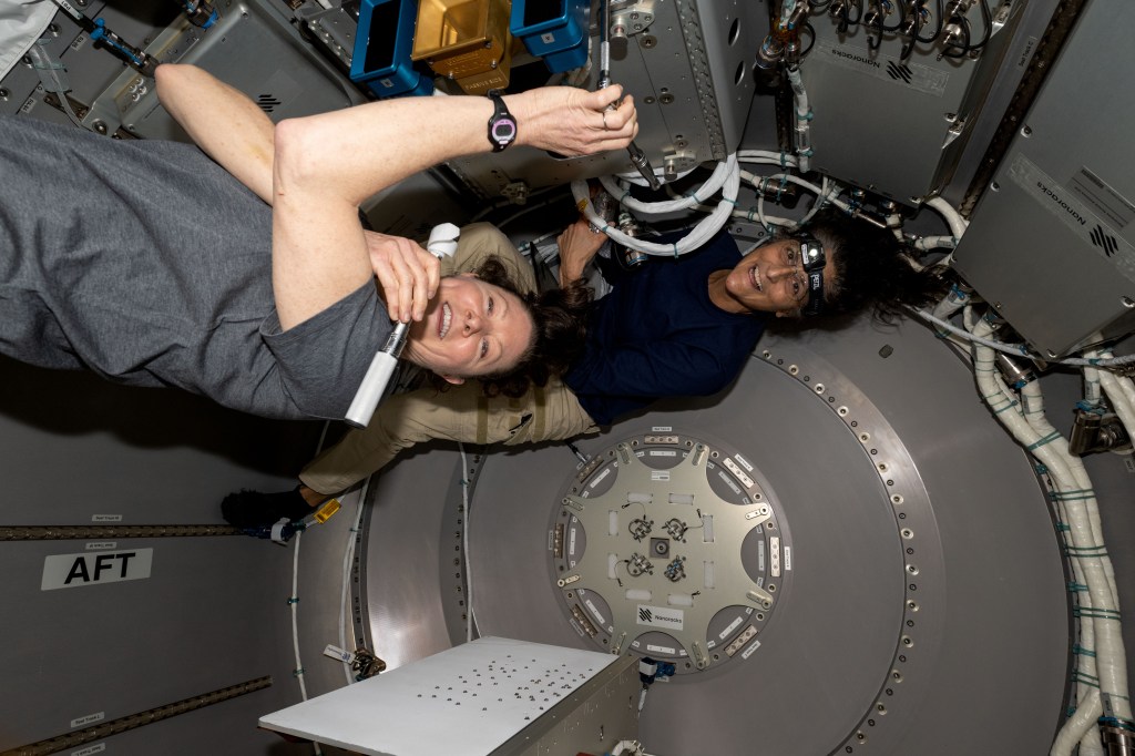 NASA astronauts (from left) Tracy C. Dyson, Expedition 71 Flight Engineer, and Suni Williams, Pilot for Boeing's Crew Flight Test, work inside the NanoRacks Bishop airlock located in the port side of the International Space Station's Tranquility module. The duo installed the the ArgUS Mission-1 technology demonstration hardware inside Bishop for placement outside in the vacuum of space to test the external operations of communications, computer processing, and high-definition video gear.