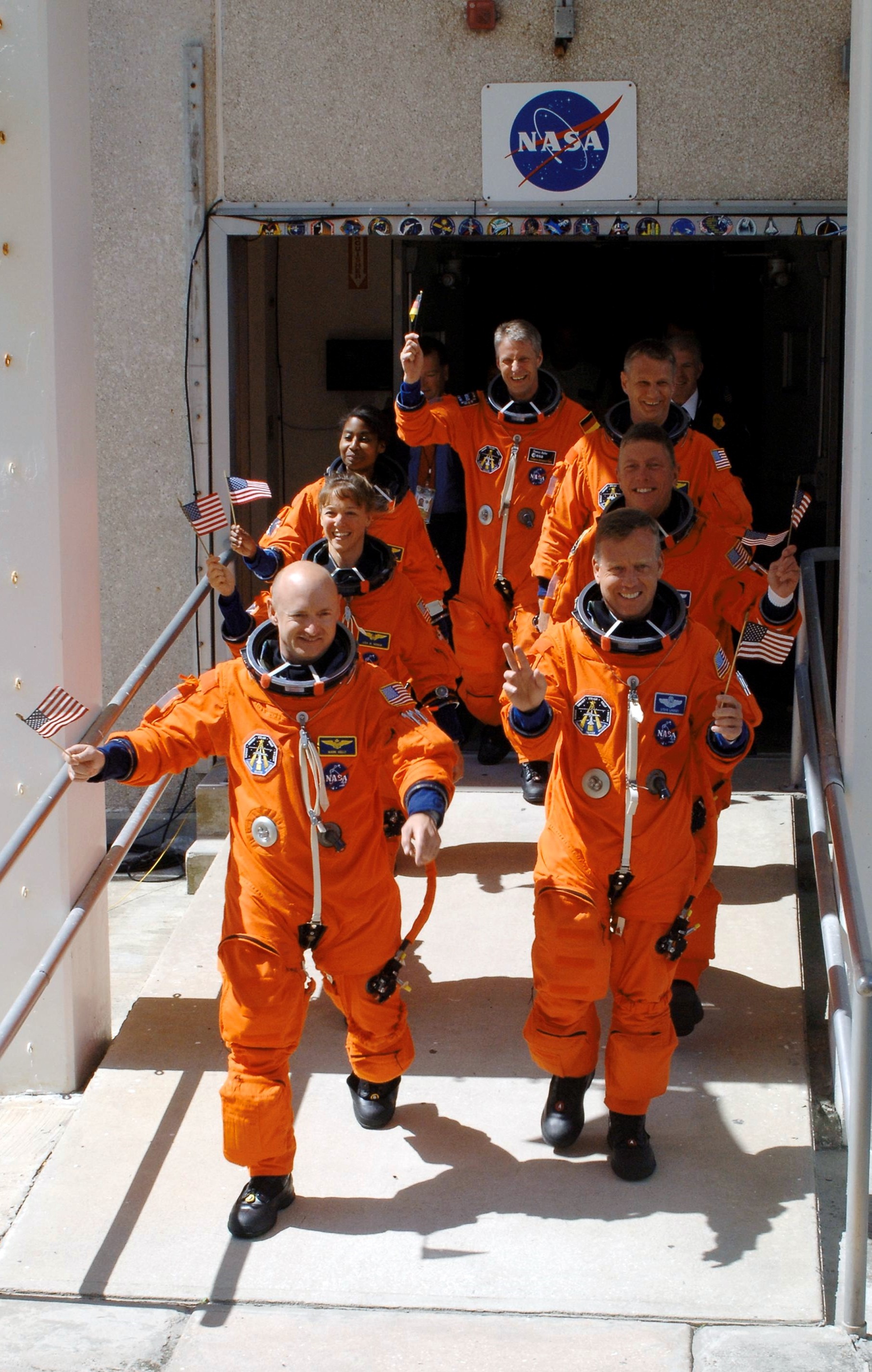 July 4, 2006. The crew of STS-121 wave American (and one German) flags as they depart crew quarters for their Fourth of July launch