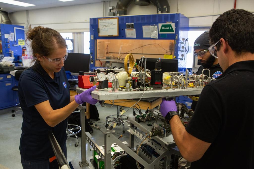 From left, team members Annie Meier, Malay Shah and Jamie Toro assemble the flight hardware for NASA’s Orbital Syngas Commodity Augmentation Reactor, or OSCAR, on Oct. 10, 2019, in the Space Station Processing Facility at the agency’s Kennedy Space Center in Florida. OSCAR is an Early Career Initiative project at the spaceport that studies technology to convert trash and human waste into useful gasses such as methane, hydrogen and carbon dioxide. By processing small pieces of trash in a high-temperature reactor, OSCAR is advancing new and innovative technology for managing waste in space. A prototype has been developed, and the team is in the process of constructing a new rig for a suborbital flight test.