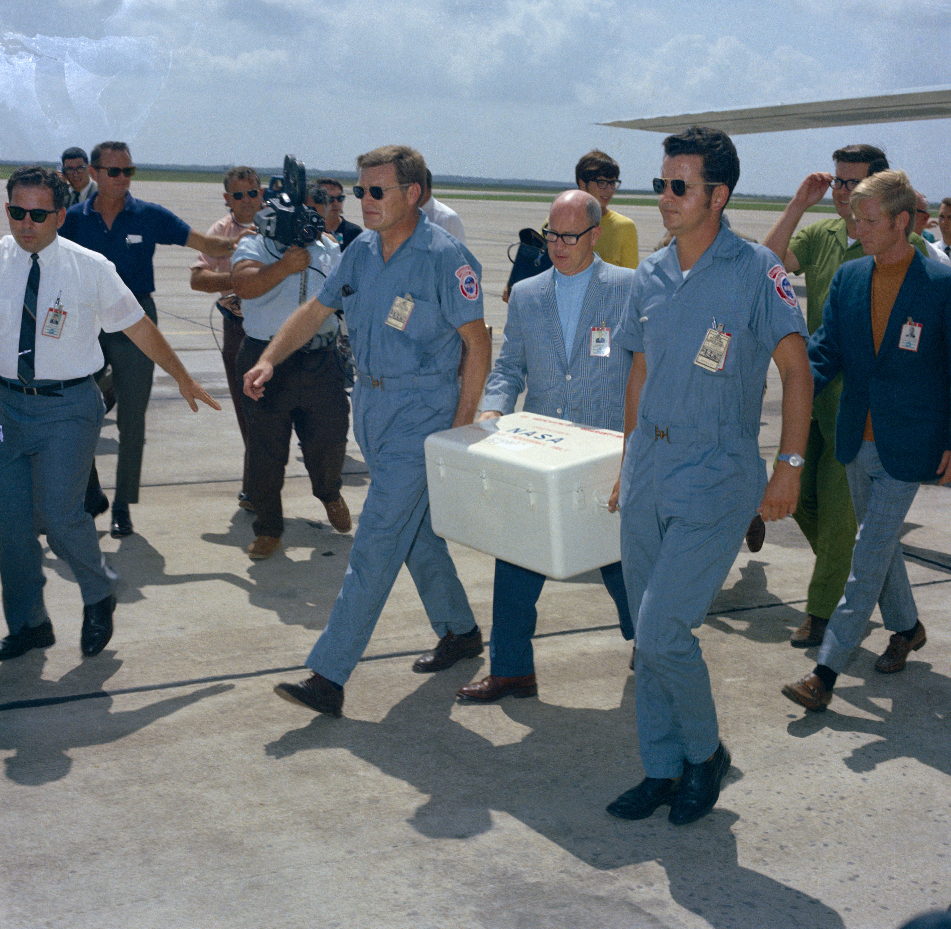 NASA officials Howard Schneider and Gary McCollum carry the first box of Moon rocks from the cargo plane to a waiting car for transport to the LRL at MSC