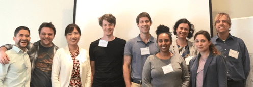 8 people standing close together smiling at the camera