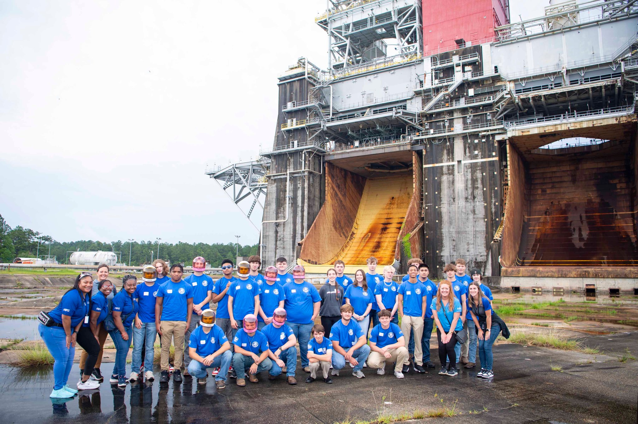 a group of high school students pose in front of the Thad Cochran Test Stand at Stennis Space Center