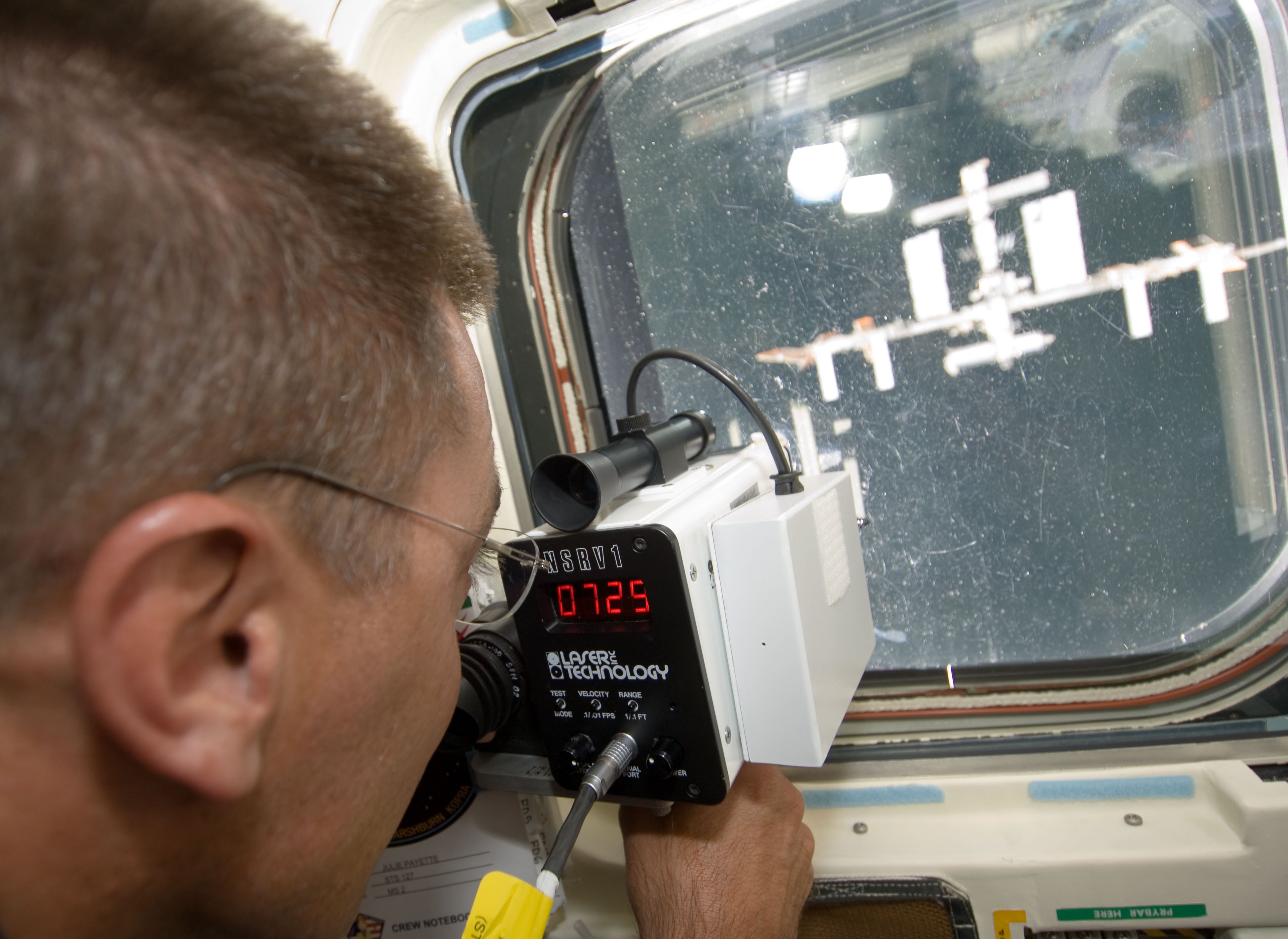 NASA astronaut Christopher J. Cassidy uses a laser range finder during Endeavour's rendezvous with the space station