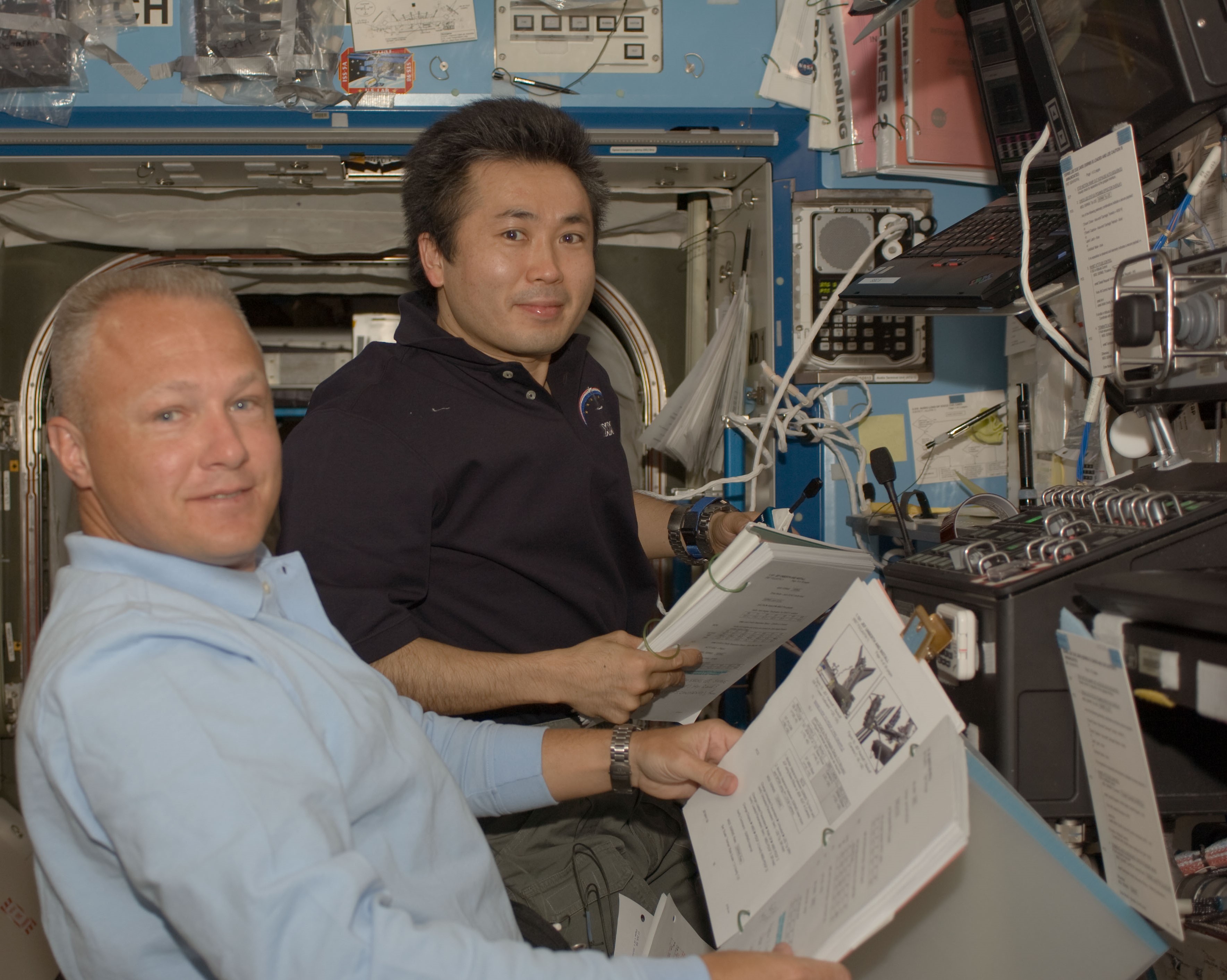 Douglas G. Hurley, left, and Koichi Wakata of the Japan Aerospace Exploration Agency operate the station's robotic arm during the first spacewalk
