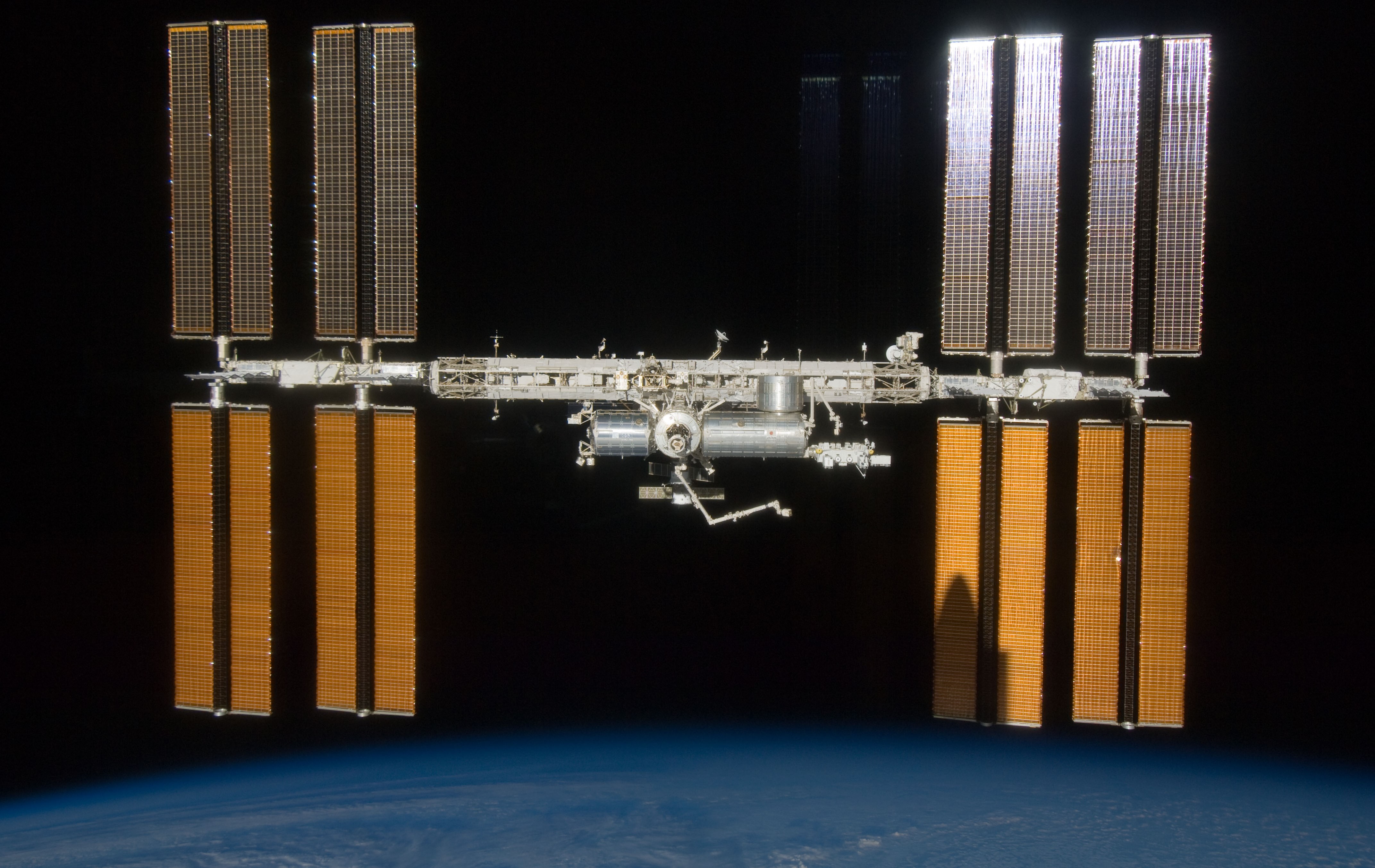 The International Space Station, with the newly added Exposed Facility and its first payloads, as seen from Endeavour during the departure flyaround. Endeavour casts its shadow on the solar arrays