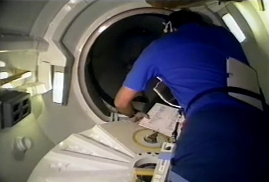 Richard J. Hieb opens the hatch from the airlock to the tunnel leading to the Spacelab module