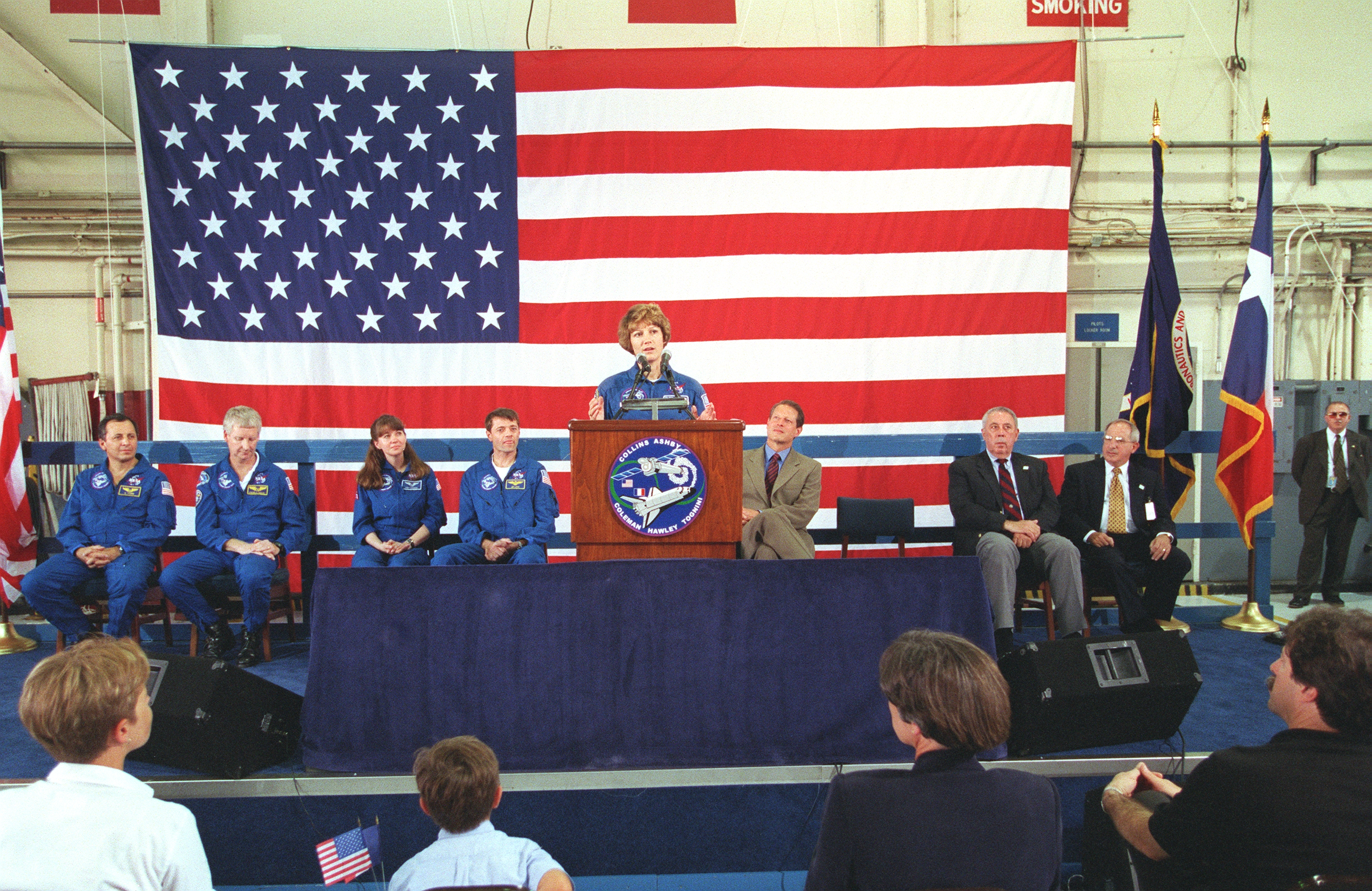 Eileen M. Collins addresses the crowd at Houston’s Ellington Field during the welcome home ceremony for the STS-93 crew, as Vice President Albert “Al” A. Gore and other dignitaries listen