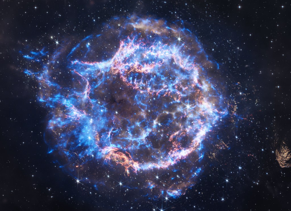 This image features the Cassiopeia A supernova, an expanding ball of matter and energy ejected from an exploding star. Here, rings of neon blue and brilliant white emit veins of polished gold. The rings and their arching veins encircle a place of relative calm at the center of the supernova remnant. This hole at the center of the circle, and the three-dimensionality conveyed by the rings and their arching veins, give this image of Cassiopeia A the look of a giant, crackling, electric blue donut. X-rays detected by Chandra show debris from the destroyed star and the blast wave from the explosion.
