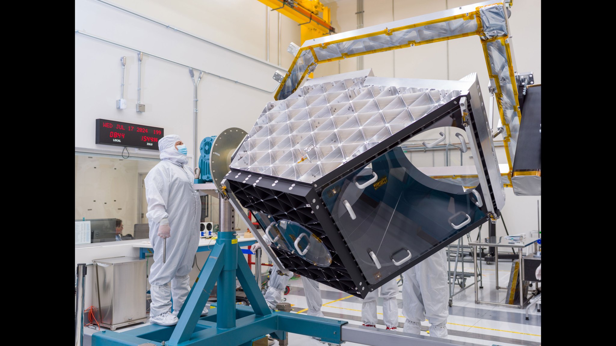 A technician operates articulating equipment to rotate NEO Surveyor’s aluminum optical bench