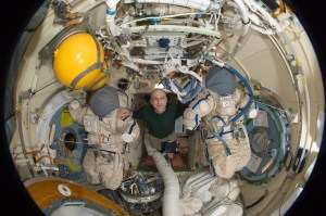 A fisheye lens attached to an electronic still camera was used to capture this image of NASA astronaut Don Pettit, Expedition 31 flight engineer, with two Roscosmos Orlan spacesuits in the Pirs Docking Compartment of the International Space Station. Credit: NASA