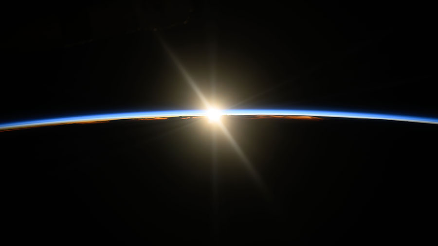 The space station was orbiting above the Pacific Ocean when this photograph captured the first rays of an orbital sunrise illuminating Earth's atmosphere.