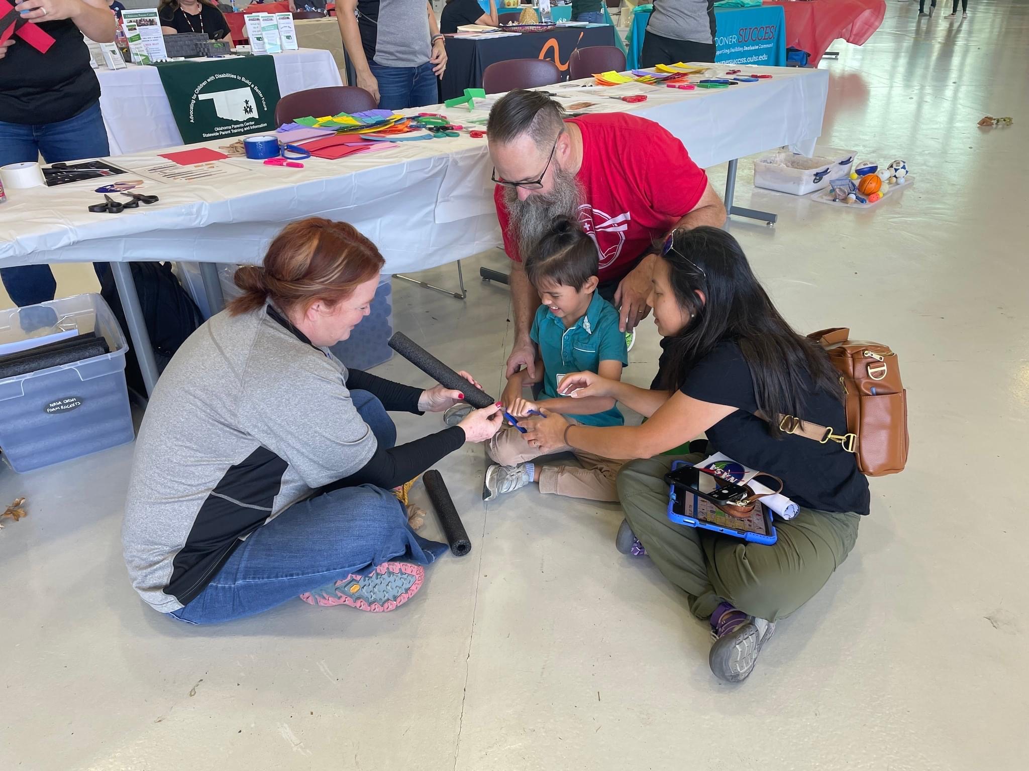 A teacher helps a child with disabilities and their parents build a foam rocket during a STEM event in Oklahoma.