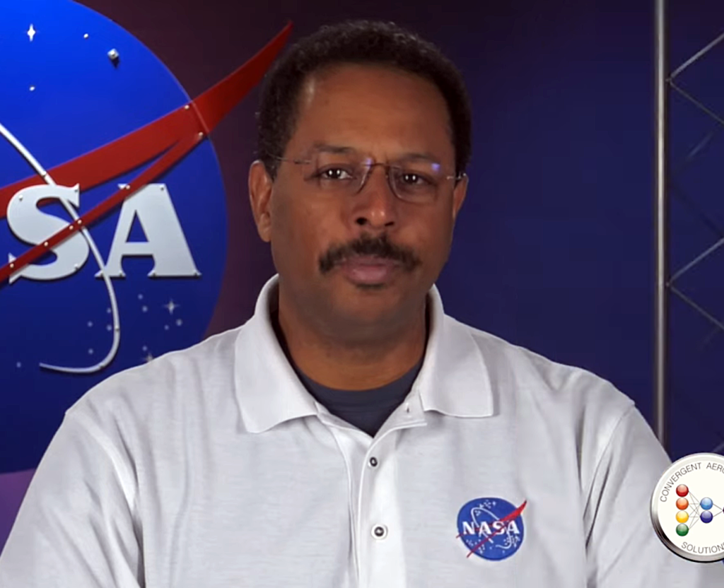 A man wearing a white shirt with a NASA logo on it.