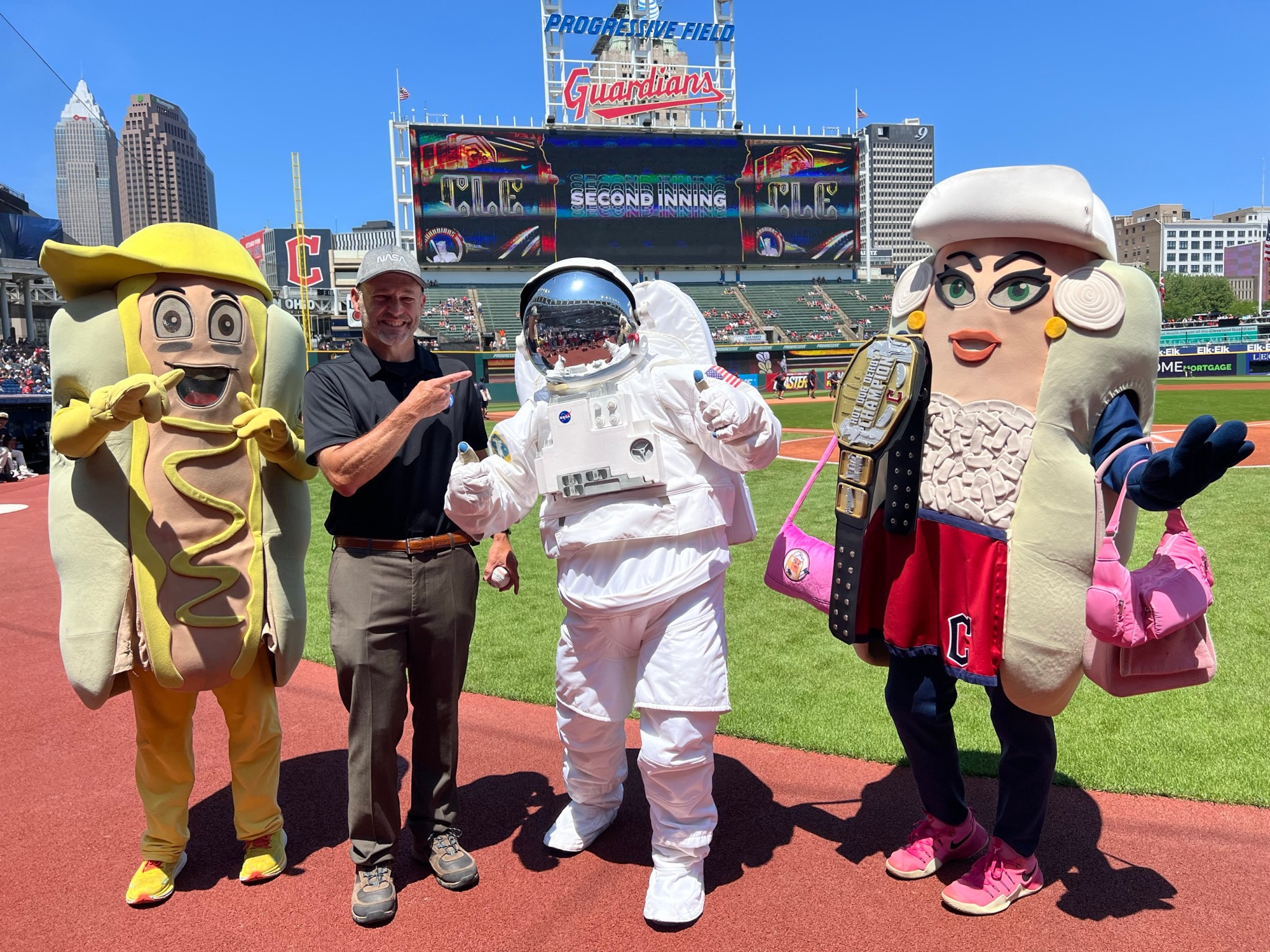 NASA Glenn Center Director Dr. Jimmy Kenyon, second from left, stands with mascots Mustard, Eva the Astronaut, and Onion on the field after the hog dog derby.