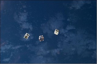 Three CubeSat packages fly in space.