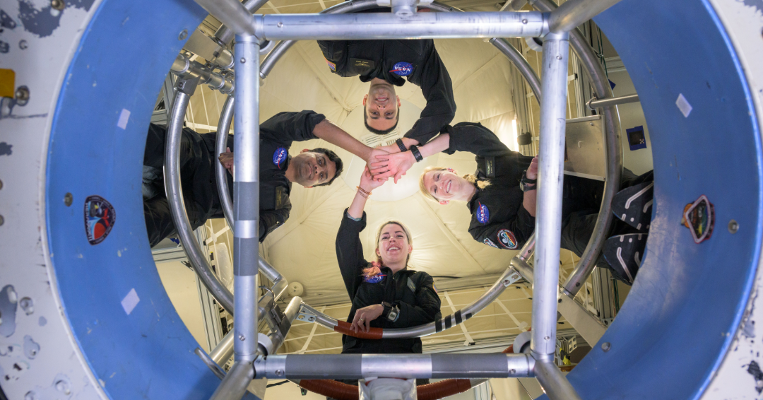 The crew of the Human Exploration Research Analog’s Campaign 7 Mission 1 clasp hands above their simulated space habitat’s elevator shaft.