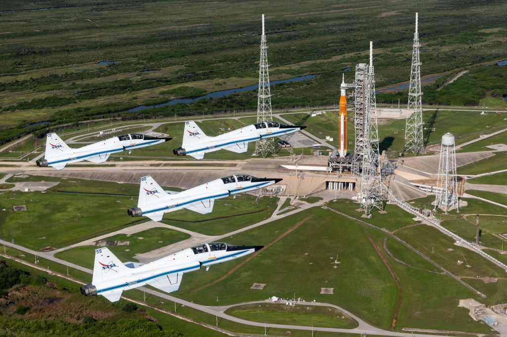 Four NASA T-38 Talon jets fly in formation over Kennedy Space Center.