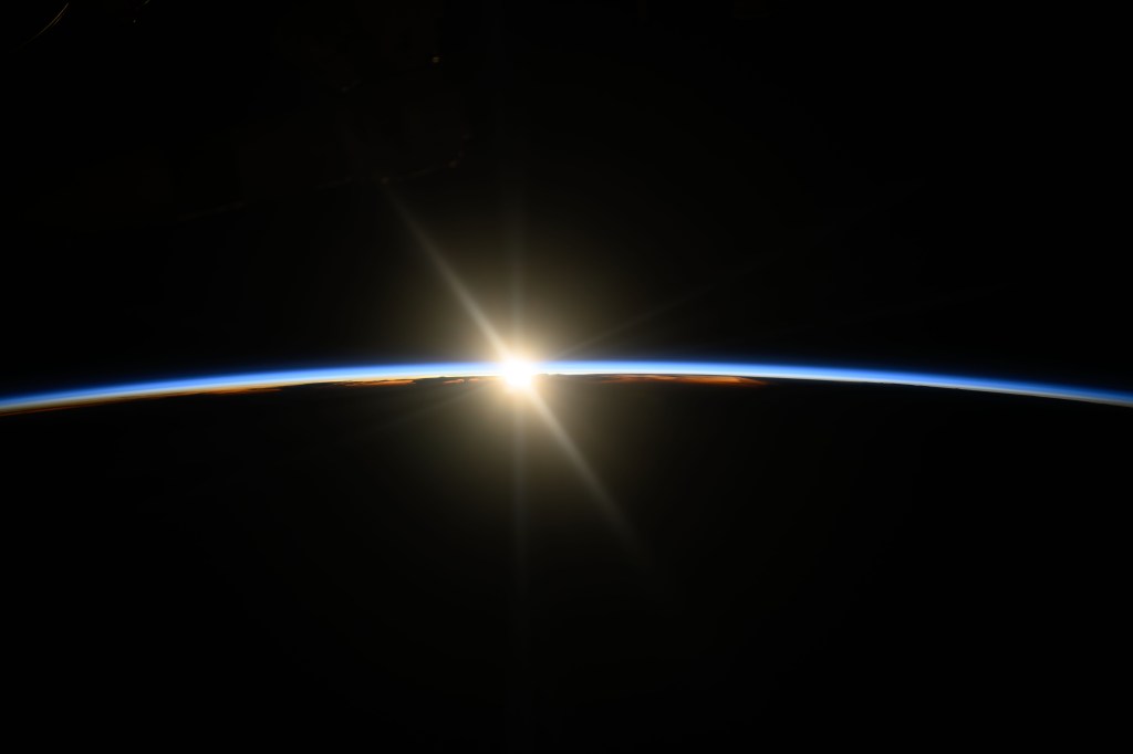 The International Space Station was orbiting on a northeast track 261 miles above the Pacific Ocean when this photograph captured the first rays of an orbital sunrise illuminating Earth's atmosphere.