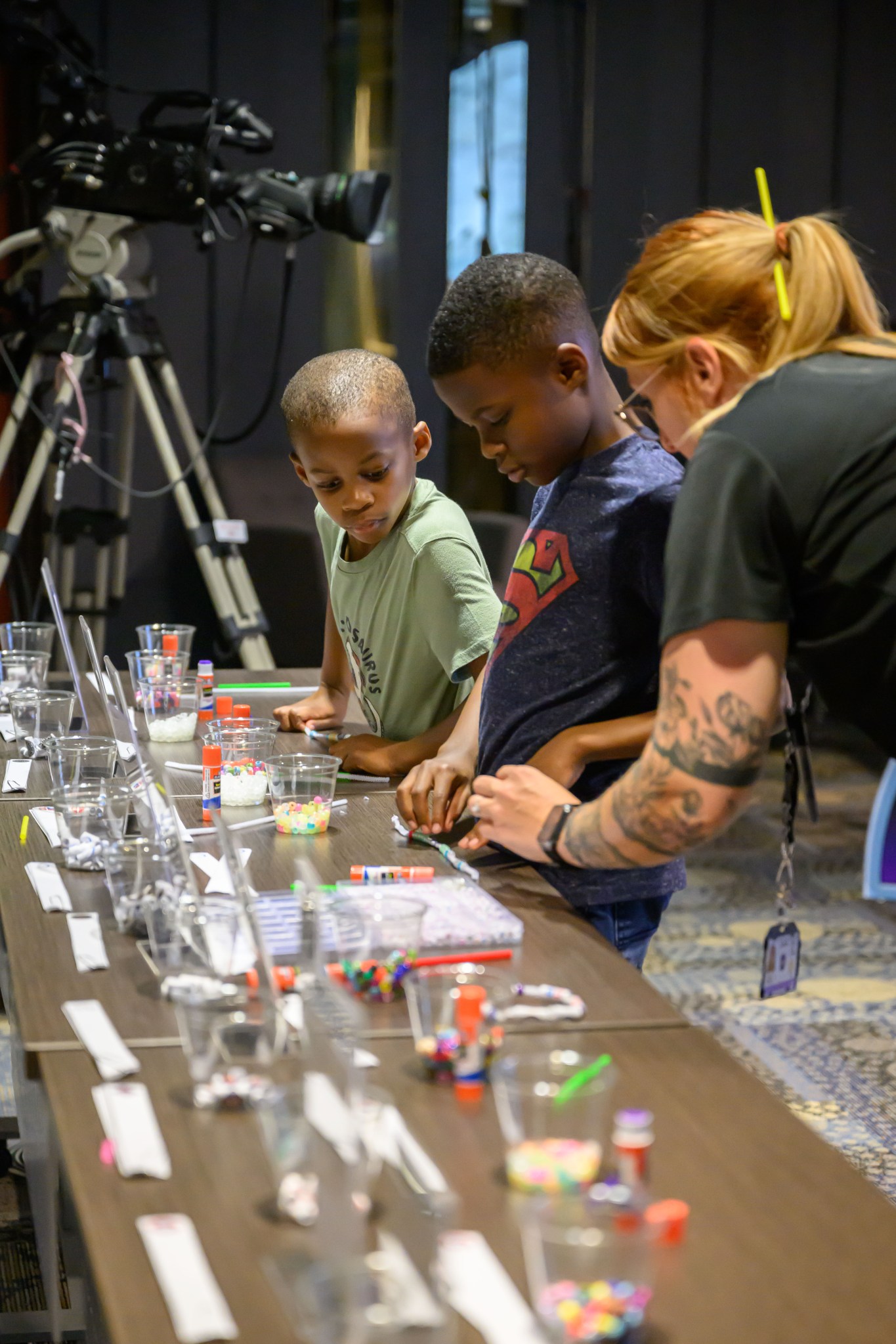 A teacher interning at Johnson Space Center helps youth guests with an activity during Bring Youth to Work Day 2024.