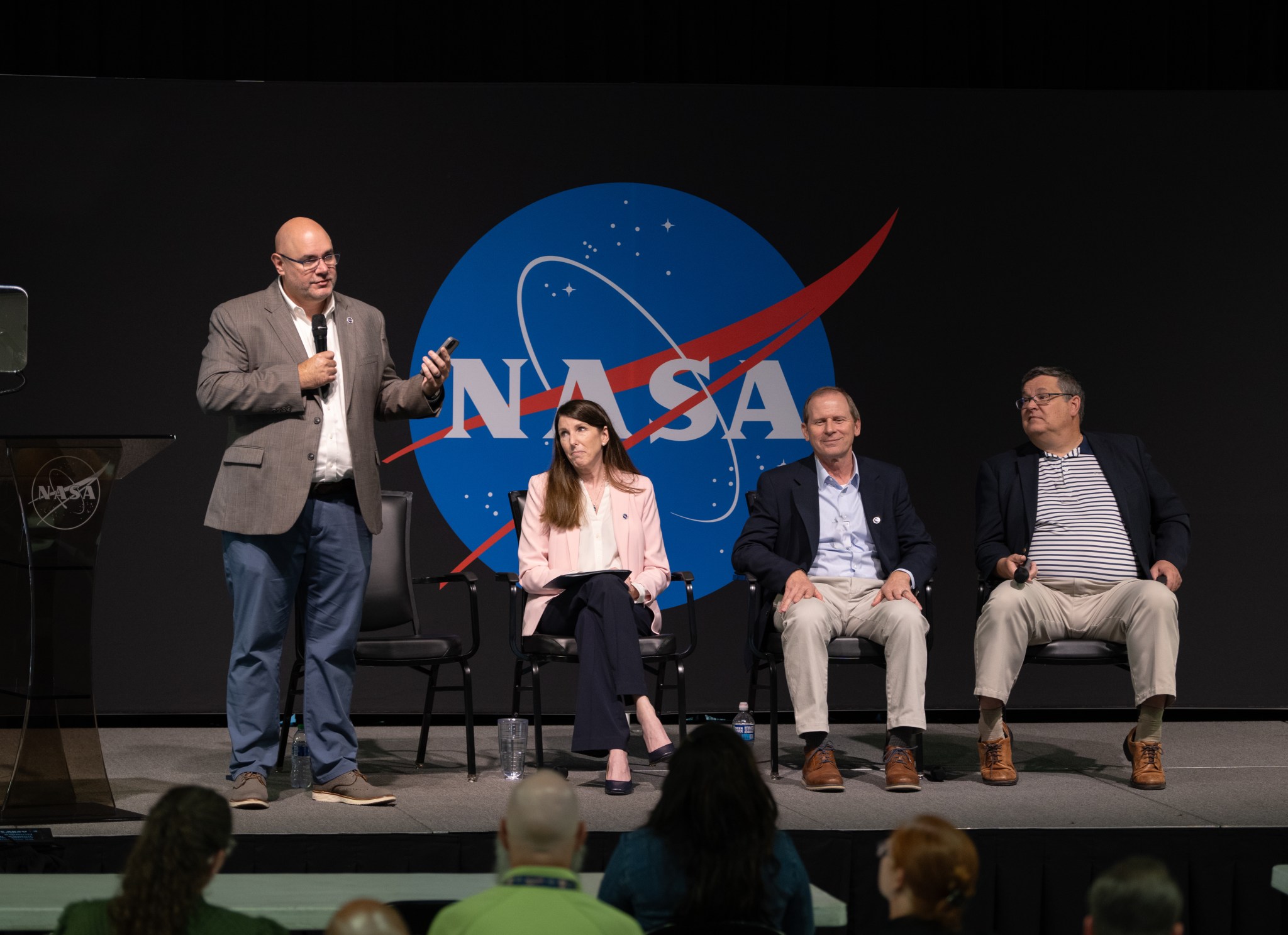 NASA Marshall Space Flight Center Director Joseph Pelfrey, left, speaks to team members during the all-hands meeting Aug. 26 in Building 4316. Joining Pelfrey on stage, from left, are Rae Ann Meyer, deputy director; Roger Baird, associate director; and Larry Leopard, associate director, technical.