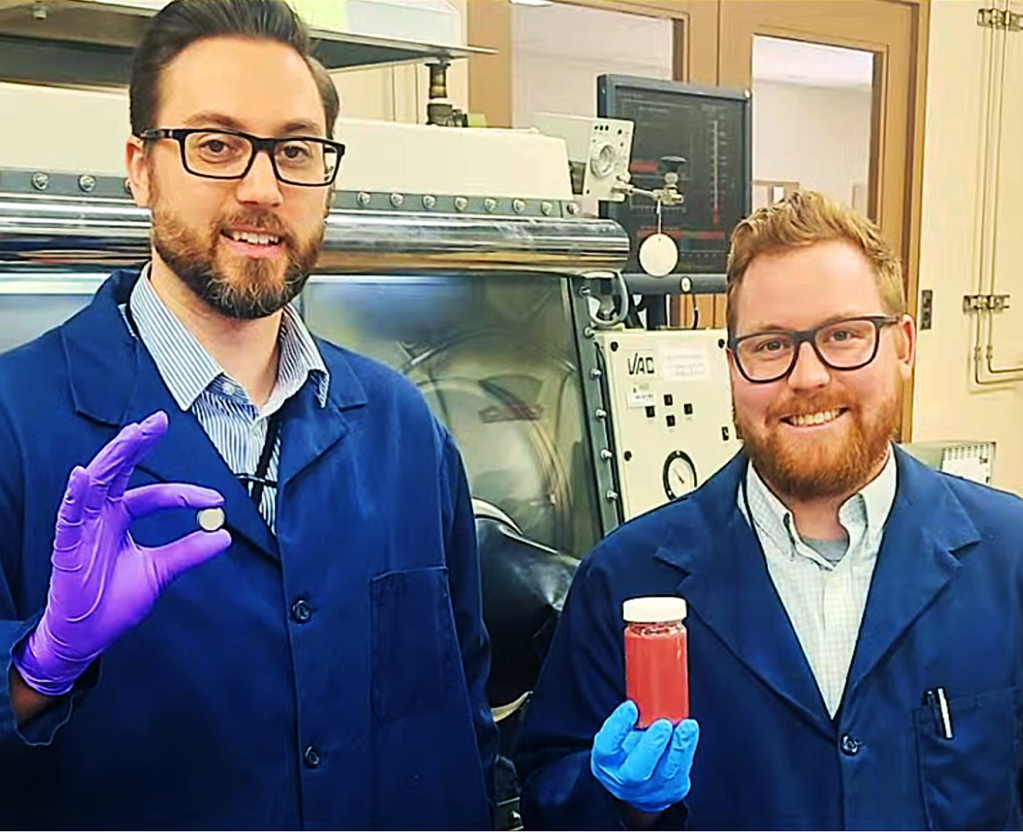 Two men in blue lab coats pose for a picture.