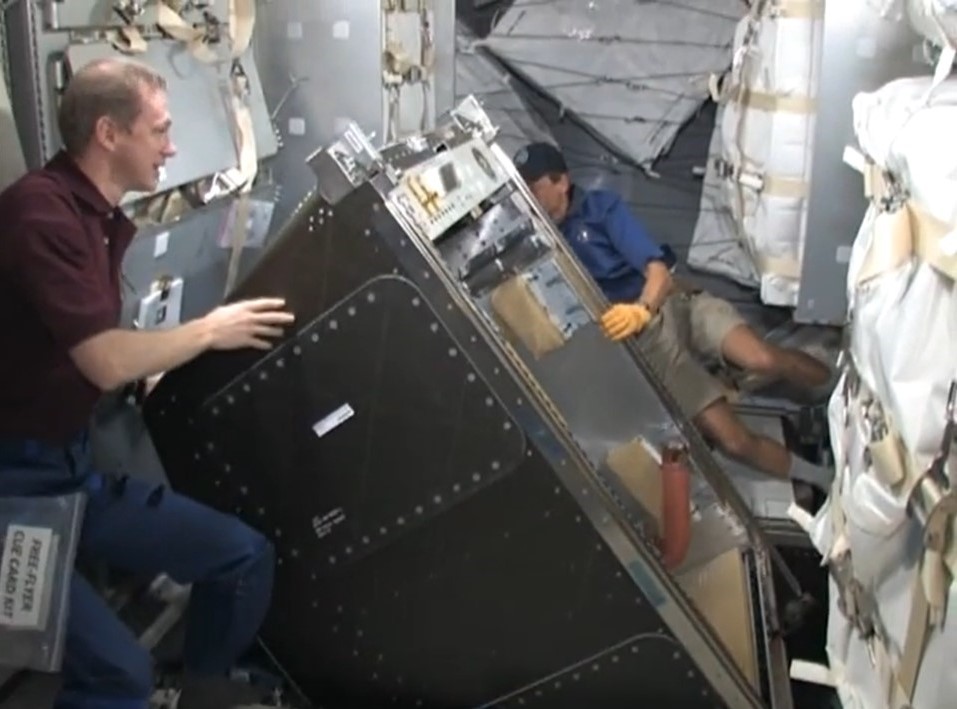 DeWinne, left, and Fuglesang begin the transfer of the T2 COLBERT treadmill from the MPLM to the space station