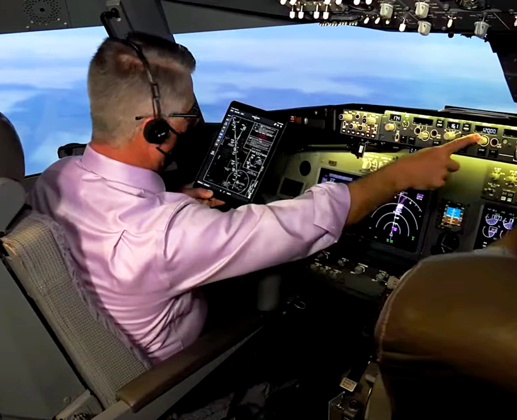 A pilot sits in the left seat of the cockpit of an airliner.