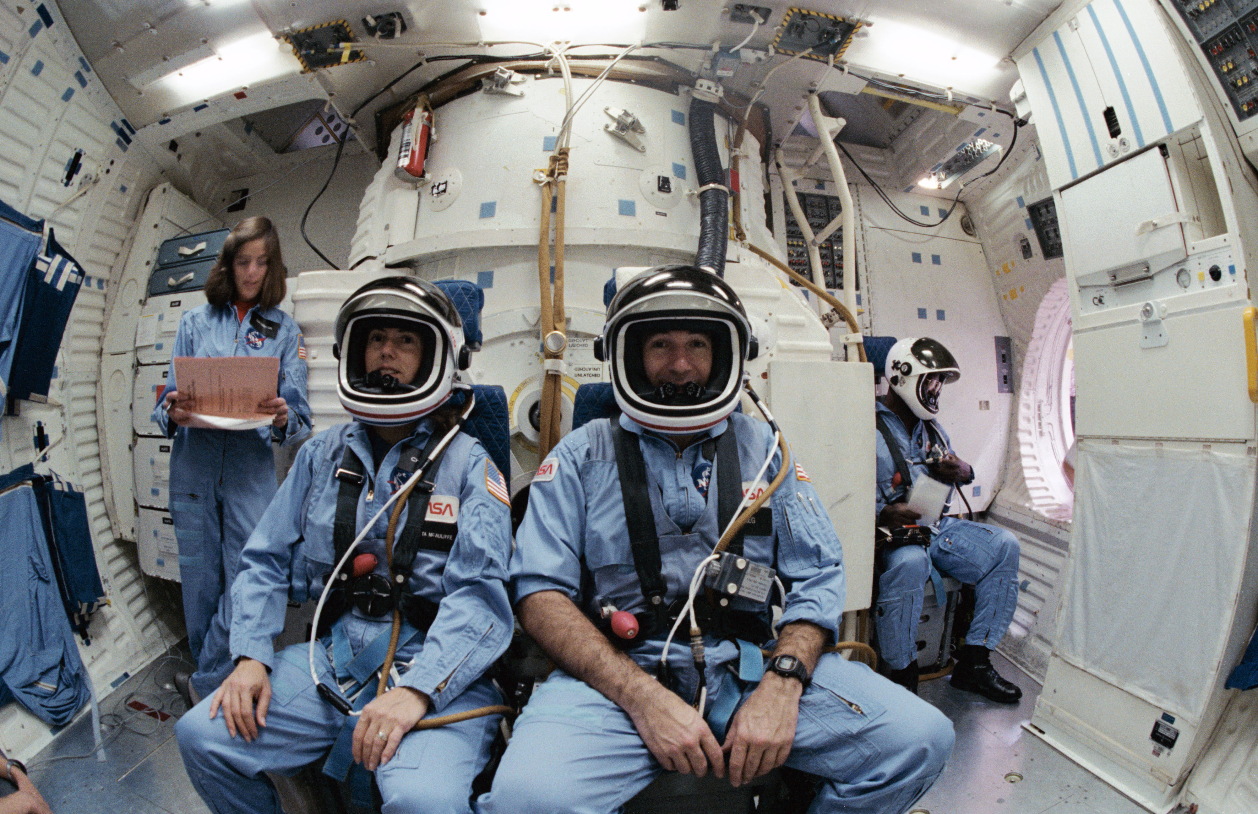 Backup Teacher in Space Barbara R. Morgan, left, prime Teacher in Space S. Christa McAuliffe, Payload Specialist Gregory B. Jarvis, and Mission Specialist Ronald E. McNair in the middeck of the Shuttle Mission Simulator