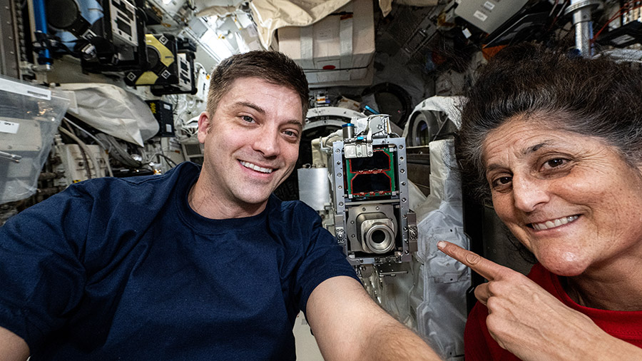 NASA astronauts Matthew Dominick and Suni Williams smile for a selfie portrait aboard the International Space Station's Kibo laboratory module.