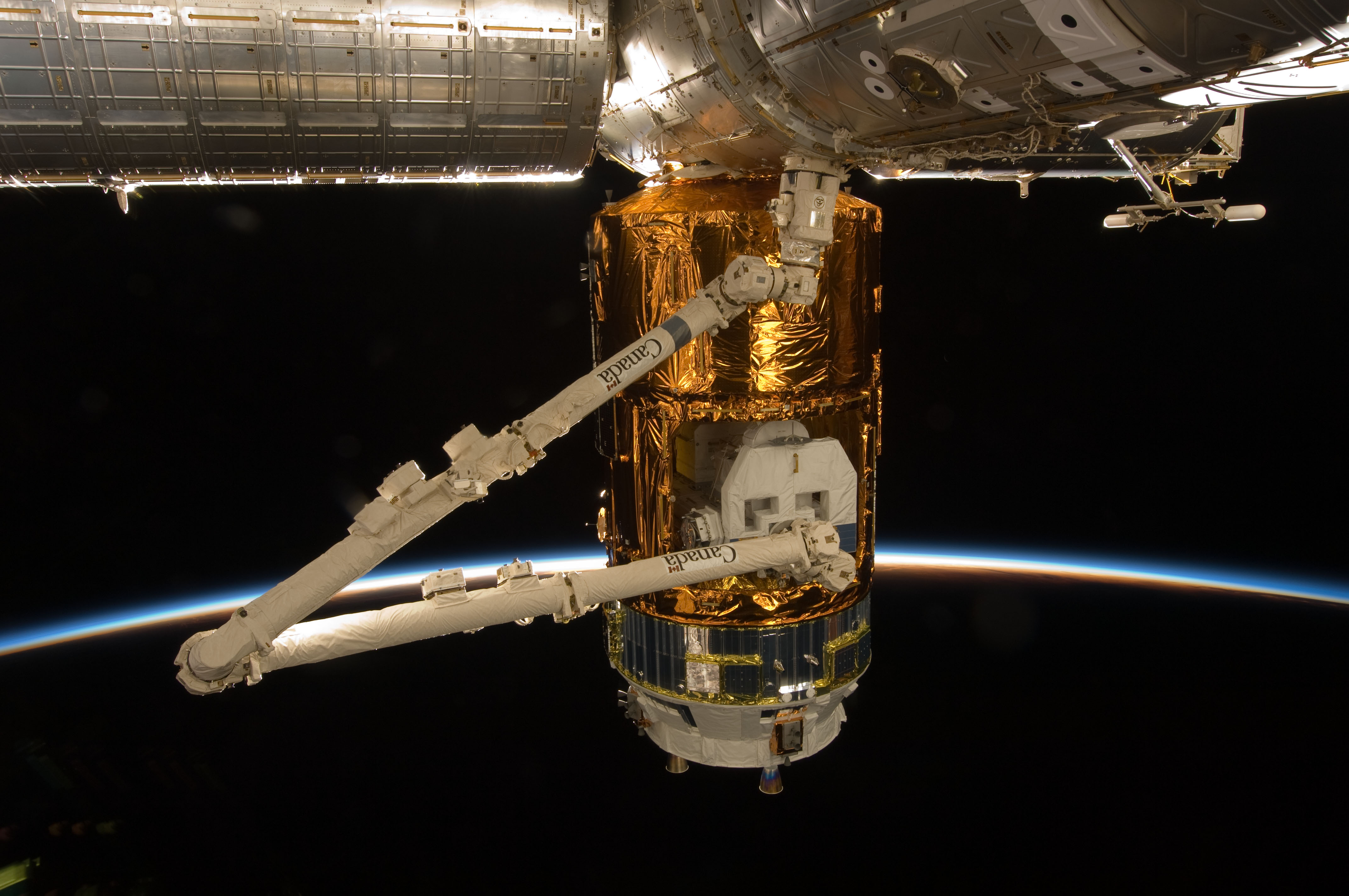 The space station’s robotic arm grapples the Exposed Pallet (EP) to transfer it to the Japanese Experiment Module-Exposed Facility (JEM-EF)