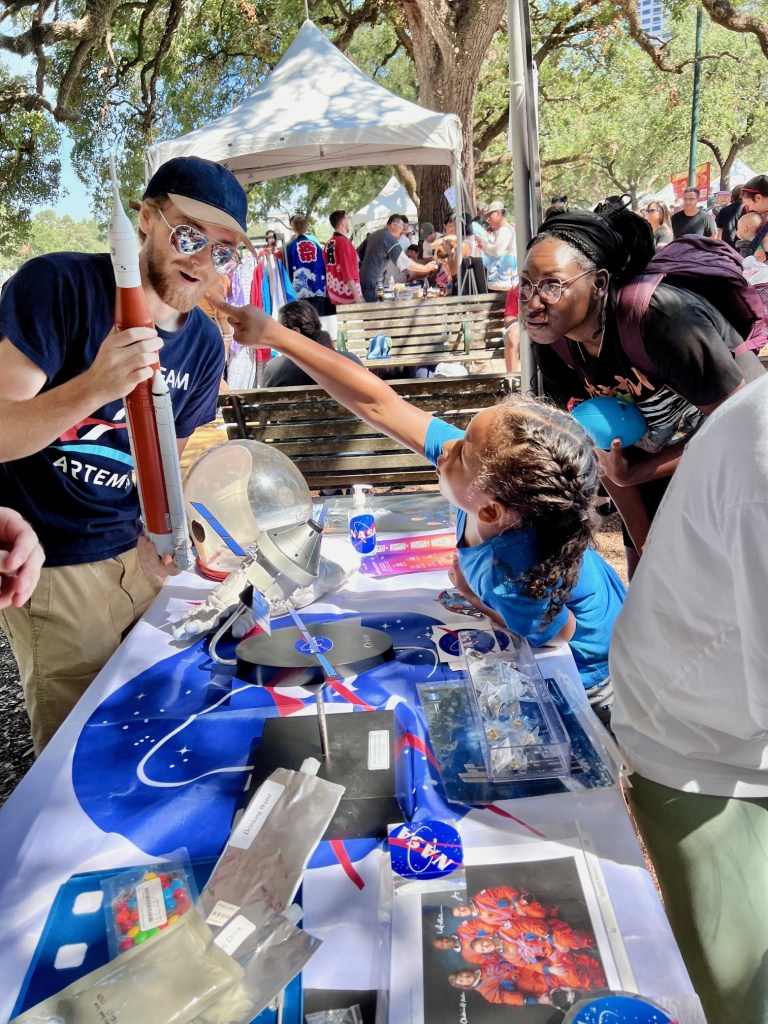 A child points to a rocket as a NASA volunteer holds it in his hands.