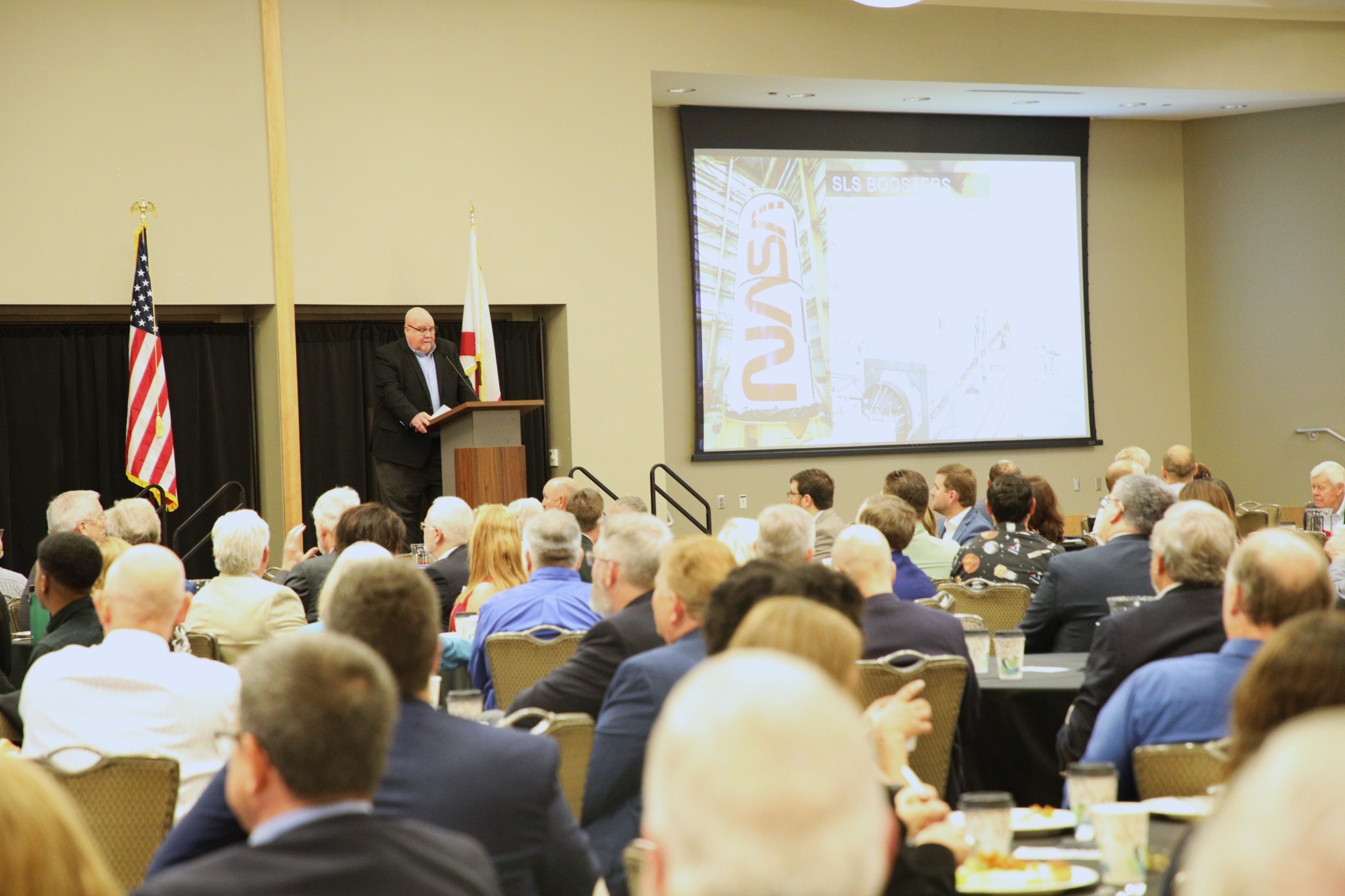 John Honeycutt, front center, manager of NASA’s SLS (Space Launch System) Program at the agency’s Marshall Space Flight Center, delivers the keynote address at the National Space Club Breakfast on Sept. 17 in Huntsville. Honeycutt provided a detailed presentation to the audience with insight into the operations, accomplishments, and future goals for the SLS Program. The SLS rocket is a powerful, advanced launch vehicle for a new era of human exploration beyond Earth’s orbit. “All elements of the SLS Block I for the first crewed lunar mission of the 21st century are either complete and ready for stacking or are nearing completion,” Honeycutt said. “For more than 60 years, this town – this community – has led the effort to explore space. We aren’t done. SLS and Artemis are the next chapter in that legacy. Led and enabled by folks in this room, at Marshall, and here in North Alabama, we will launch missions to the Moon that will re-write history books, lead to scientific discoveries, and pave the way to Mars.”