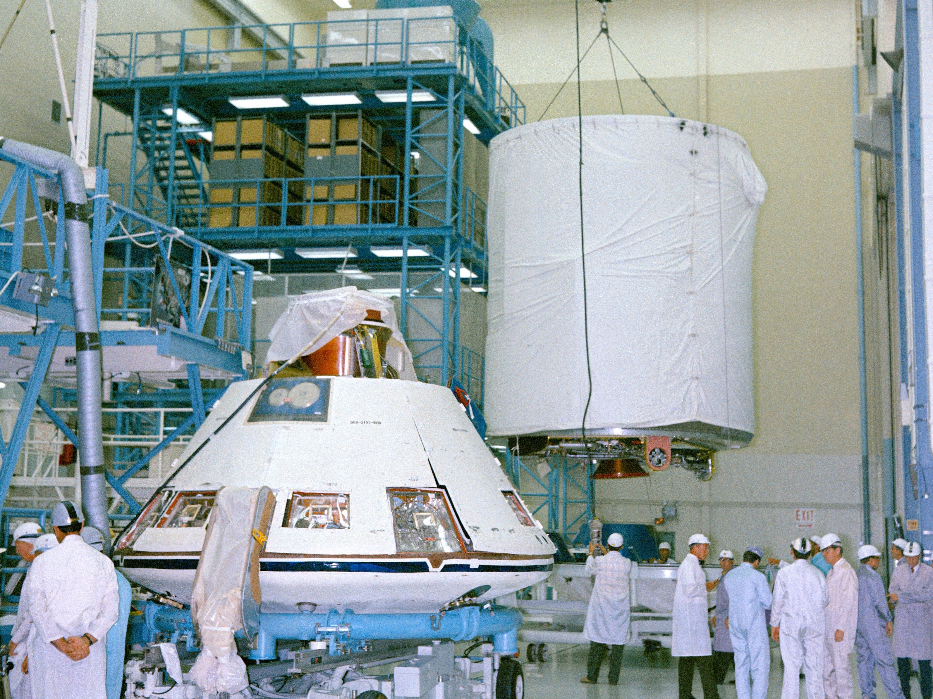 At North American Rockwell’s (NAR) Downey, California, facility, workers assemble the Apollo 14 Command Module (CM), left, and Service Module